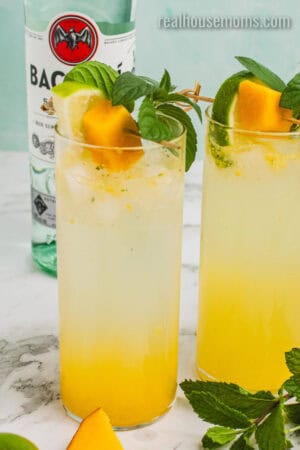 mango mojito garnished with mango cubes, lime wedge, and fresh mint