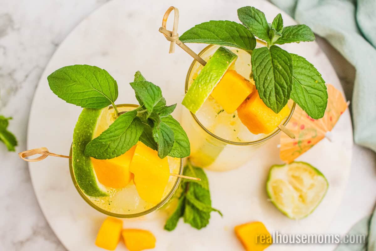 looking down at two mango mojitos on a marble serving tray