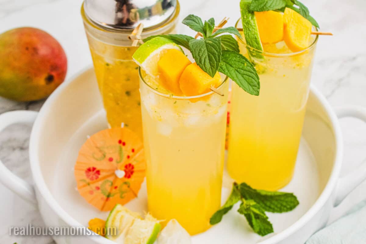 mango mojitos on a tray next to the cocktail shaker