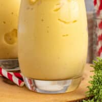 mango pineapple smoothie in a glass with a straw with recipe name at the bottom