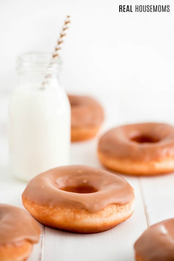 maple donuts on a counter next to a bottle of milk