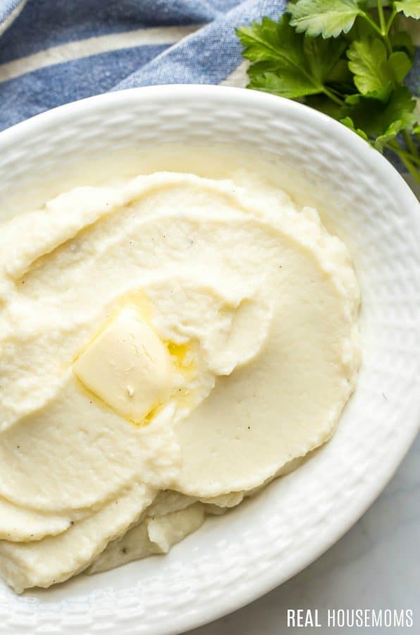 Velvety smooth Mashed Cauliflower in a serving dish topped with butter