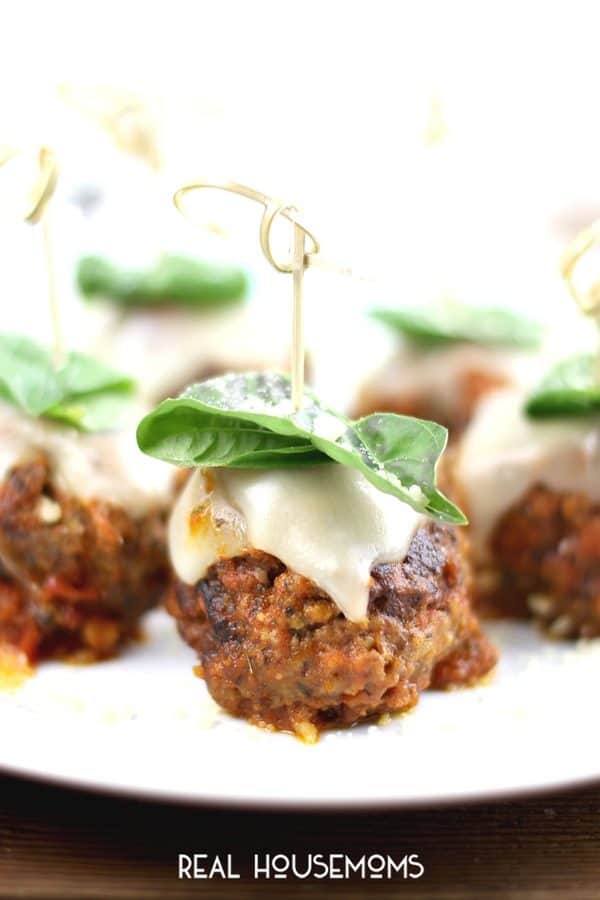 Meatball Parm bites are the perfect appetizer for your next gathering.  Tender meatballs, infused with garlic, breadcrumbs, and parmesan, smothered in red sauce and topped with melted mozzarella and fresh basil.