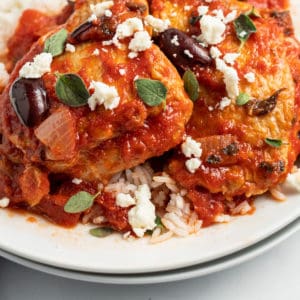 close up of chicken thighs in red sauce over rice