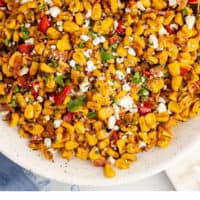 serving bowl of mexican blackened corn with a spoon with recipe name at the bottom