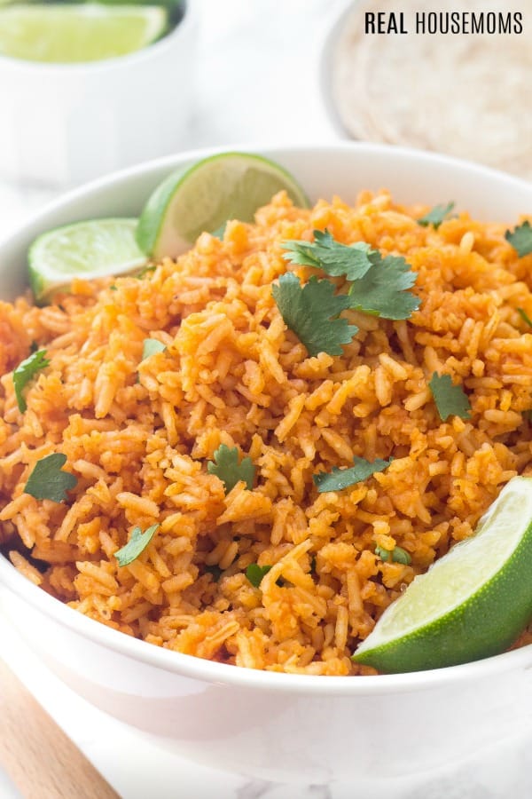 mexican rice recipe in a bowl garnished with cilantro and lime wedges