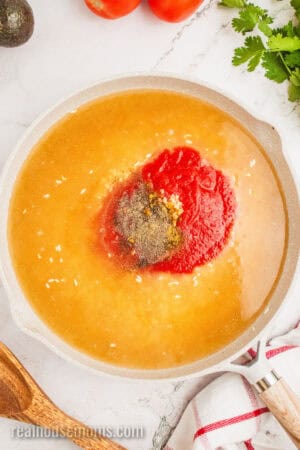 tomato sauce, vegetable stock, garlic, and seasonings in a skillet with toasted rice