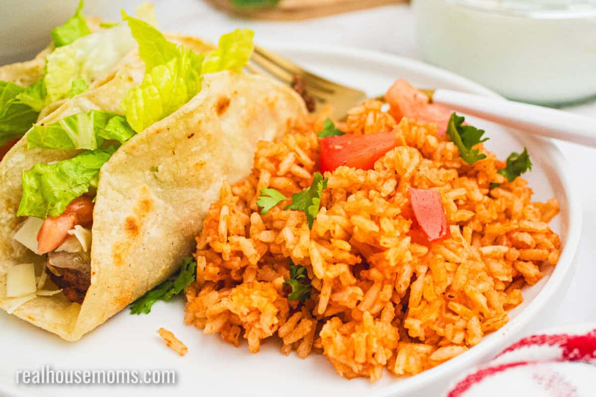 mexican rice served on a plate with two tacos