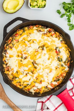 shredded cheddar and pepper jack cheese meted over top of mexican spinach dip in a skillet