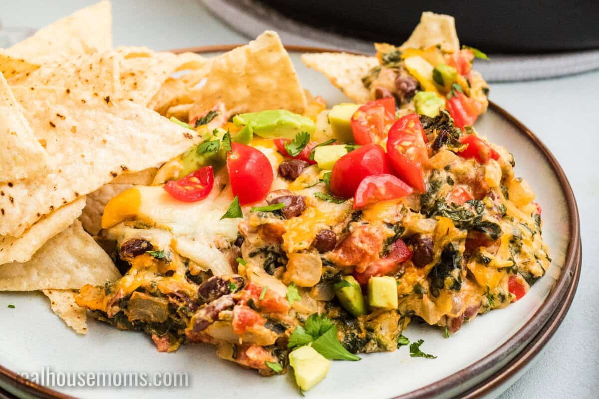 portion of mexican spinach dip on a plate with tortilla chips