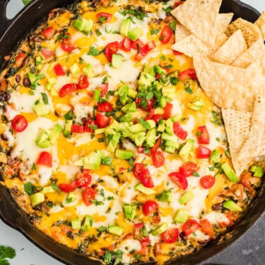square image of mexican spinach dip in a skillet with tortilla chips