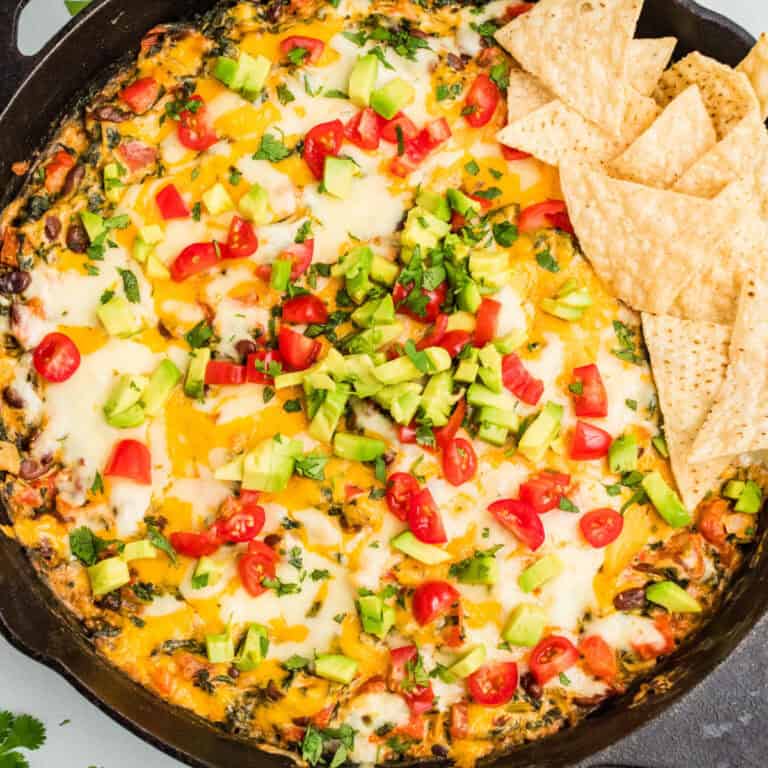 square image of mexican spinach dip in a skillet with tortilla chips
