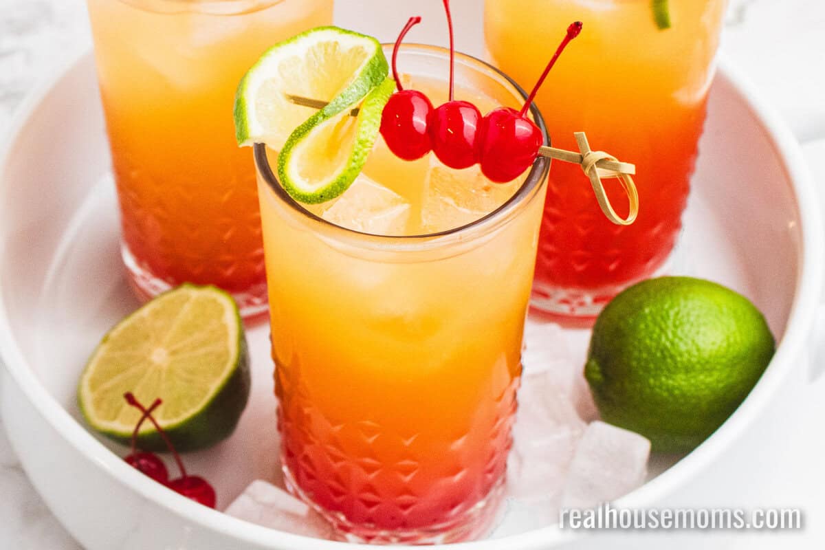 mexican sunset cocktails on a white tray with limes and ice