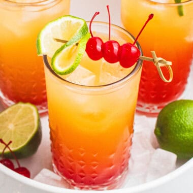 square image of mexican sunset cocktails on a white tray with ice and limes