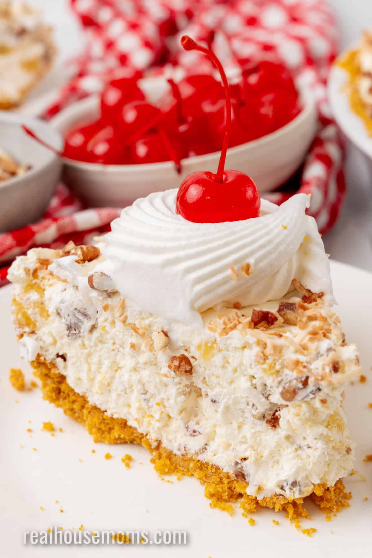 slice of million dollar pie on a small plate next to a bowl of cherries