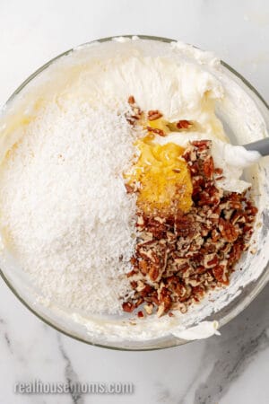 shredded coconut, pineapple, and pecans, added to a bowl of thickened sweetened condensed milk mixed with cool whip