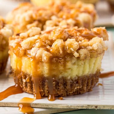 square close up image of a mini caramel apple cheesecake with caramel dripping down the sides