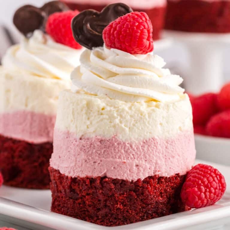 square image of mini raspberry mousse cake toped with raspberries and a chocolate heart