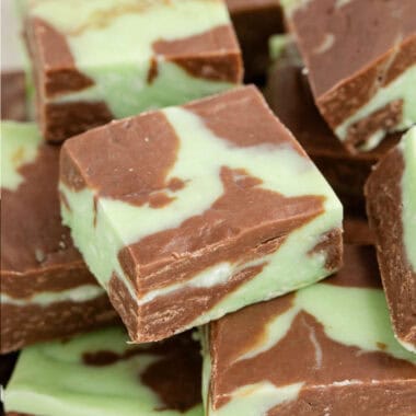 square image of mint chocolate fudge squares piled on a plate