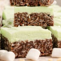 mint chocolate rice krispie treats stacked up on a wooden board with recipe name at the bottom