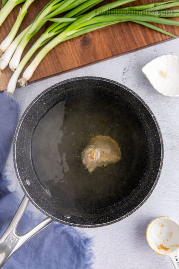 white miso pasta added to a saucepan of dashi