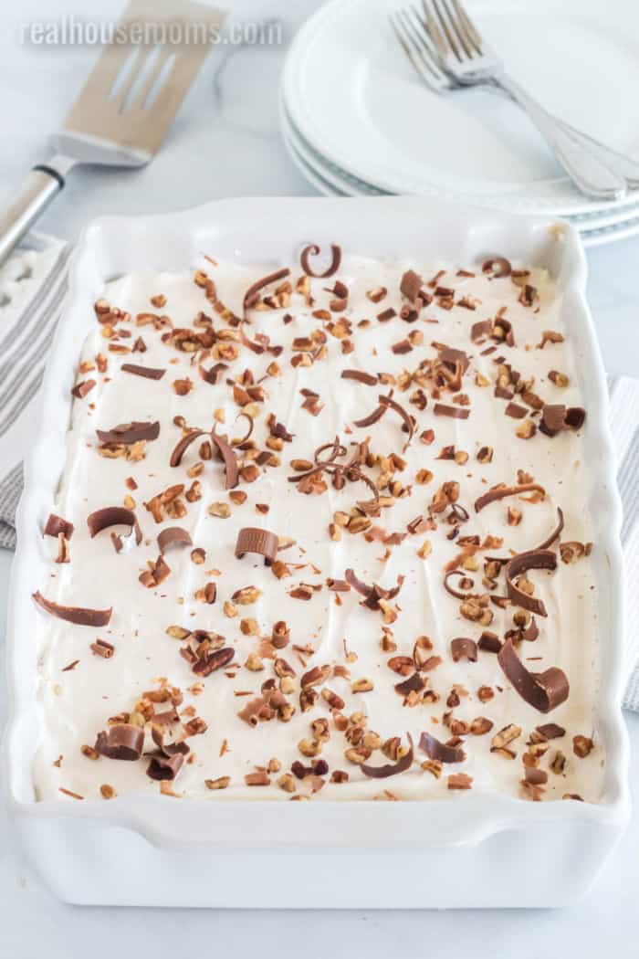 mud pie topped with whipped topping, chocolate shavings and chopped pecans in a baking dish