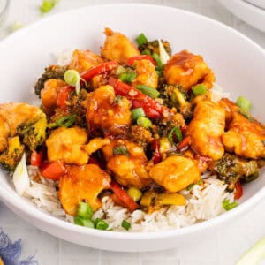 square image of Mongolian chicken over white rice in a bowl