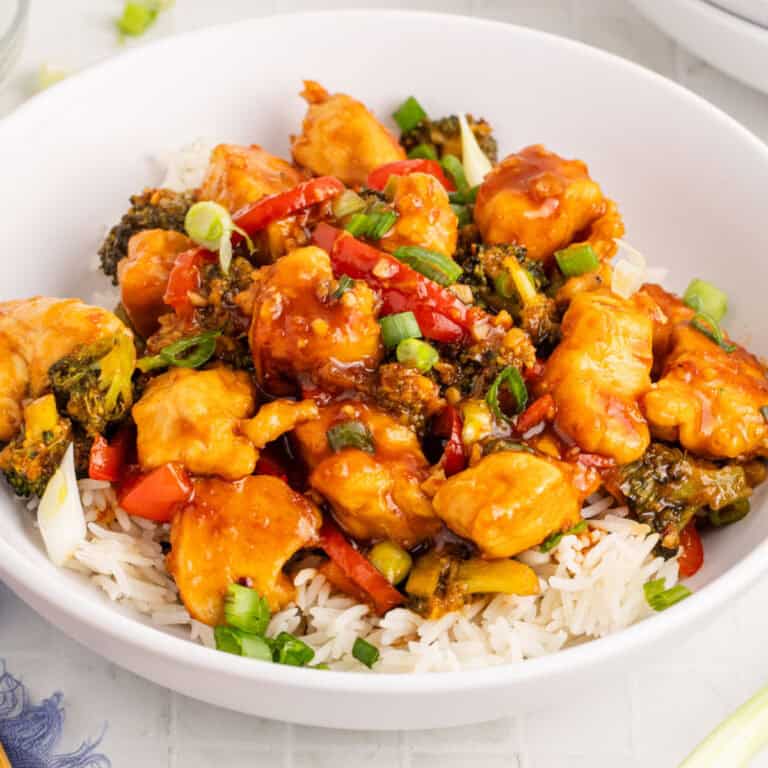 square image of Mongolian chicken over white rice in a bowl