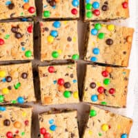 image of monster cookie bars on parchment paper with the title of the post on top of the image in pink and black lettering