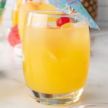 square image of a moscato pineapple punch with cocktail umbrella and cherry for garnish