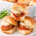 square image of three mozzarella stuffed meatball sliders stacked in a pyramid on a plate