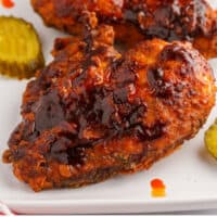 nashville hot chicken breasts on a platter with pickles with recipe name at the bottom