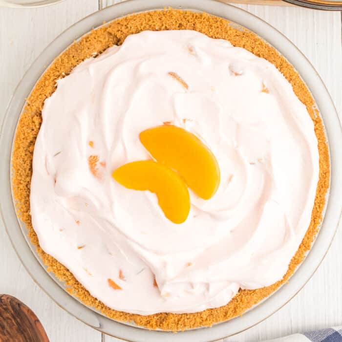 square image looking down at a no bake peach chiffon pie topped with peach slices