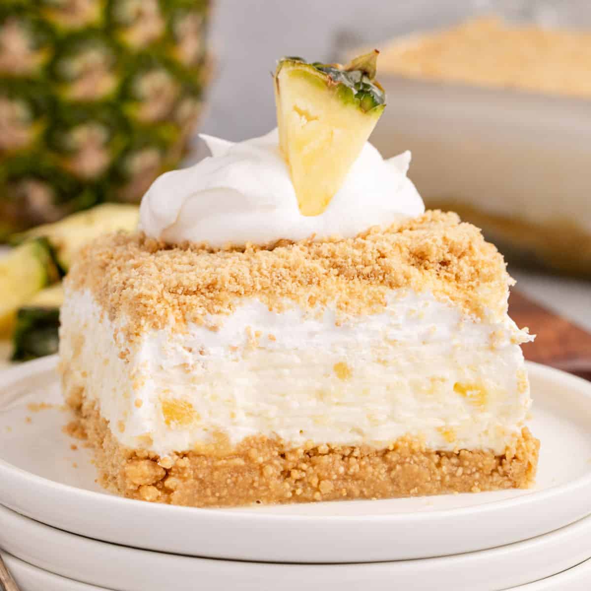 square image of pineapple dream dessert topped with cool whip and a fresh piece of pineapple on top