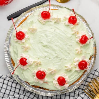 square image looking down at a no bake pistachio pie with whipped cream and cherries on top