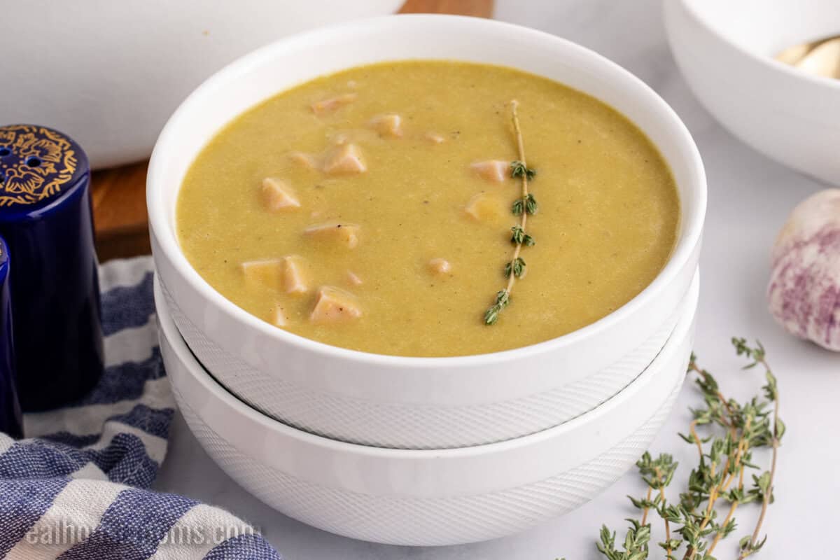 bowl of split pea soup with a sprig of fresh thyme for garnish