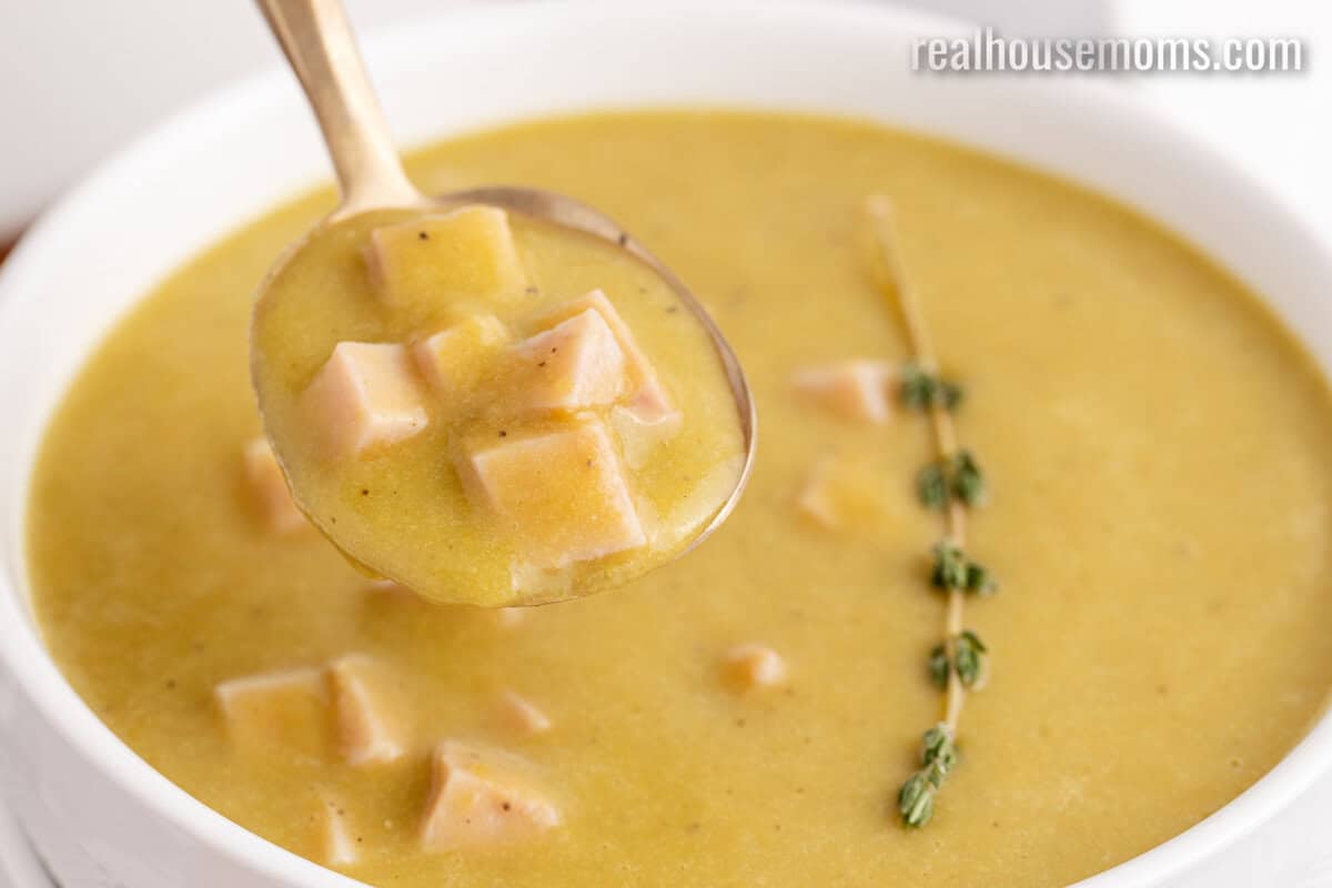 close up of a spoonful of split pea soup with ham over the bowl