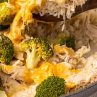 spoonful of one pot chicken and broccoli rice over the skillet with recipe name at the bottom