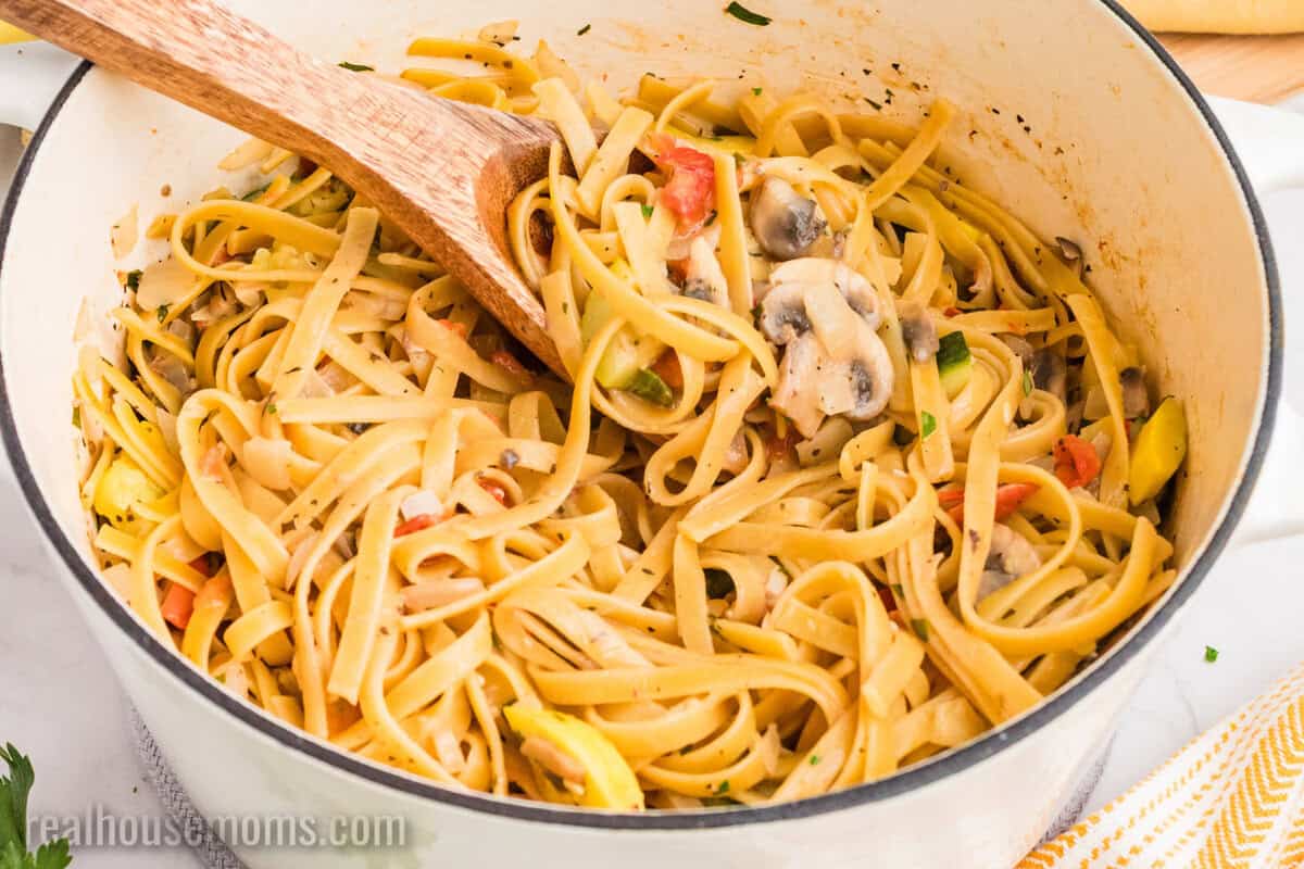 pot of summer vegetable pasta with a wooden spoon