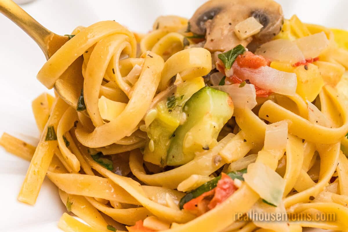 close up of a bite of summer vegetable pasta twirled onto a fork