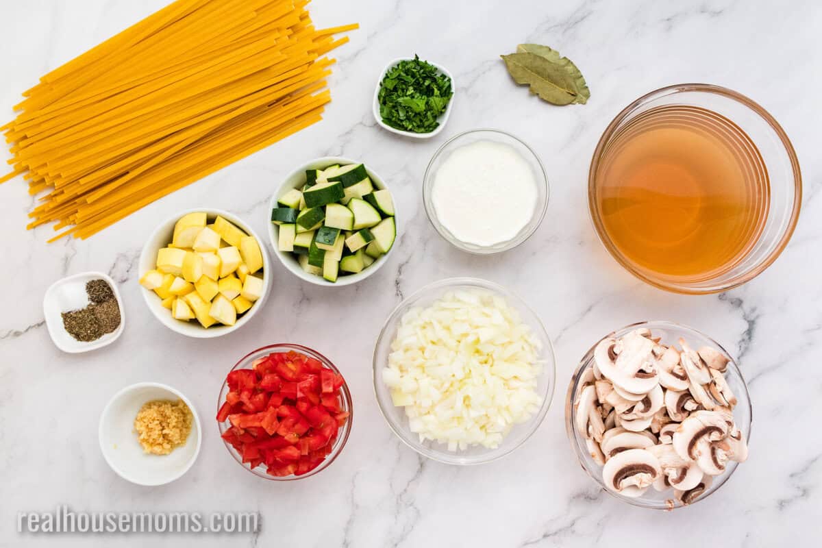ingredients to make one pot summer vegetable pasta in bowls on a counter