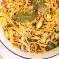 one pot vegetable pasta with bay leaves on top in a dutch oven with recipe name at the bottom