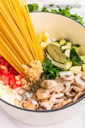 angled view of one pot vegetable pasta ingredients added to a white dutch oven