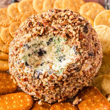 square image of an Onion Cranberry Pecan Cheese Ball with a portion taken out to show the filling