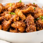 square image of orange chicken in a white serving bowl