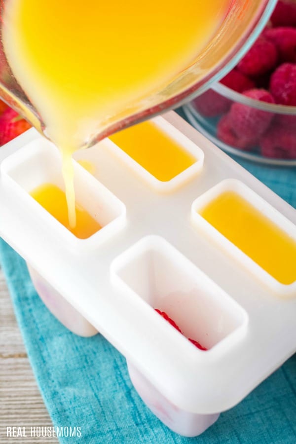 orange juice being poured into ice pop molds
