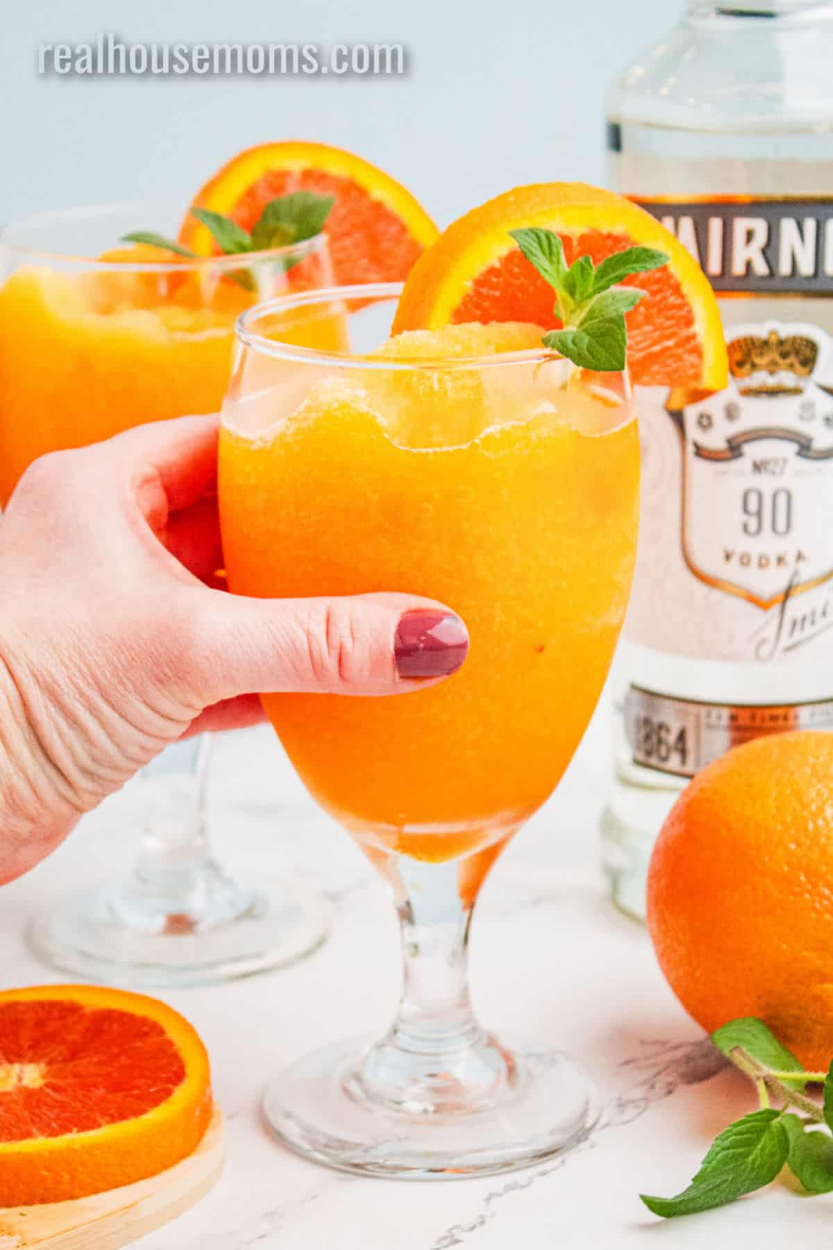 hand picking up a glass of orange vodka slush