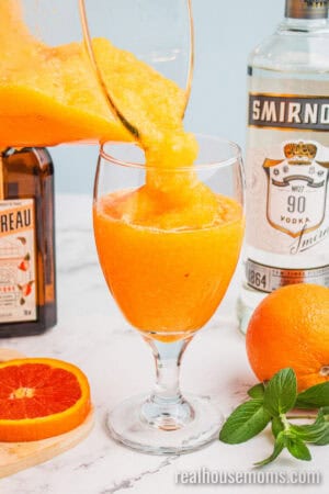 orange vodka slush being poured into a wine glass