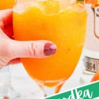 hand picking up a glass of orange vodka slush with the title of the post on the bottom of the image