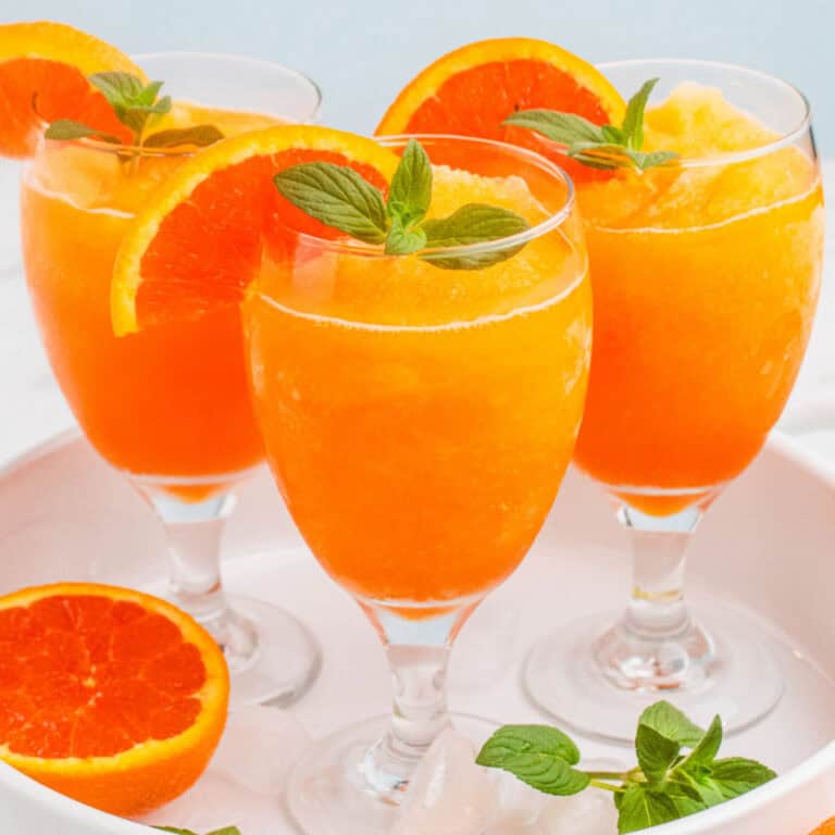 square image of three orange vodka slushes with orange slices and mint for garnish